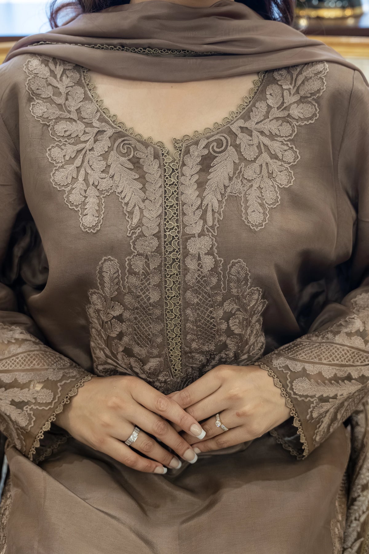 Brown embroidered garment with intricate patterns on a plain background