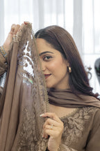 Woman wearing a brown traditional outfit with intricate lace details.